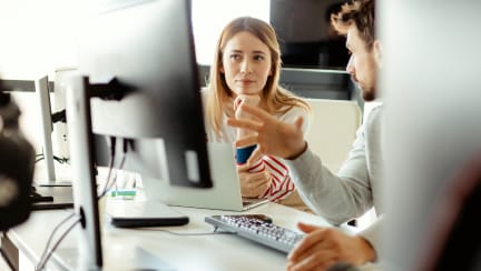 オフィスでモニターを見ている2人の同僚